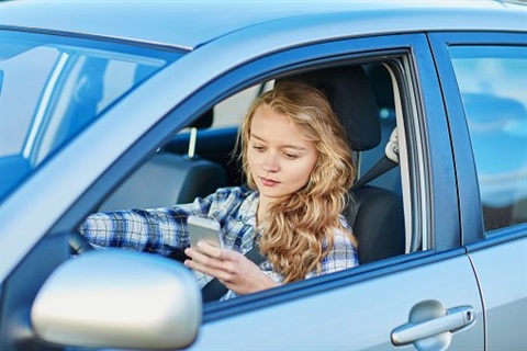 Girl looking at her phone while driving